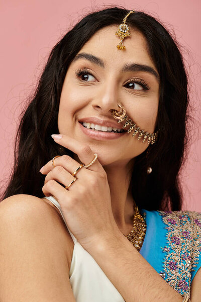 Красивая молодая индийская женщина изящно позирует в потрясающем сине-белом сари с изысканными украшениями.