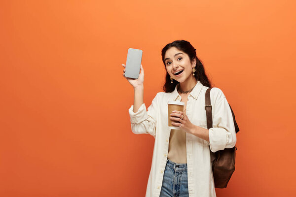Young indian woman multitasking with phone and coffee cup.