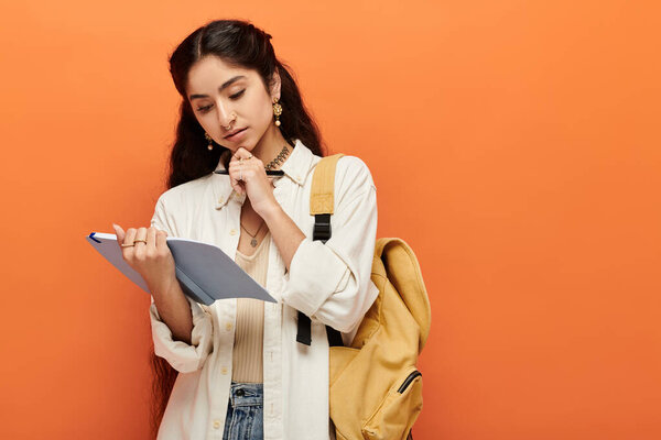 indian woman with a backpack examines clipboard attentively.