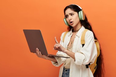 Genç Hintli kadın kulaklıkla müzik dinlerken dizüstü bilgisayar kullanıyor..
