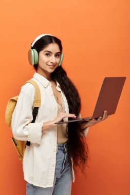 Genç Hintli kadın kulaklıkla dizüstü bilgisayar ve müzikle uğraşıyor..