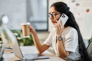 Young indian woman chatting on phone with coffee in hand. clipart