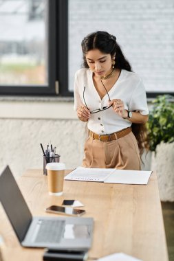 Young indian woman focused on laptop at desk. clipart