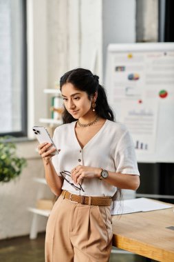Aktif genç Hintli kadın ofisteyken telefonuna sarılmış..