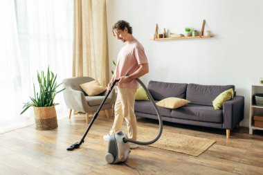 Man using vacuum cleaner in a stylish living room. clipart