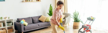 A man in a bright room cleans the floor with a mop. clipart