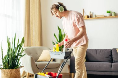 A man in cozy homewear is energetically cleaning his living room. clipart