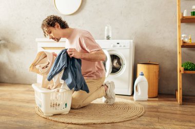 A man in cozy homewear sitting next to a washing machine. clipart