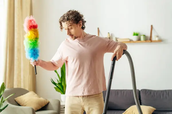 stock image A man in cozy homewear vacuums the living room.