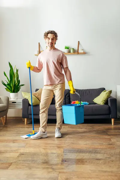 stock image A handsome man in cozy homewear mops the living room floor.