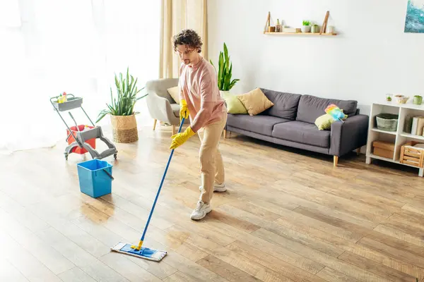 A man diligently cleans the floor with a mop in a brightly lit room.