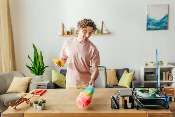 stock image A man in a pink shirt cleans a table.