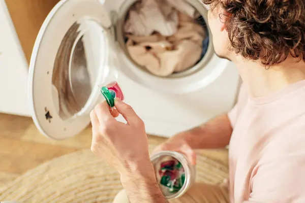 Mand Hyggeligt Hjemmetøj Holder Kop Vaskemiddel Foran Vaskemaskine - Stock-foto