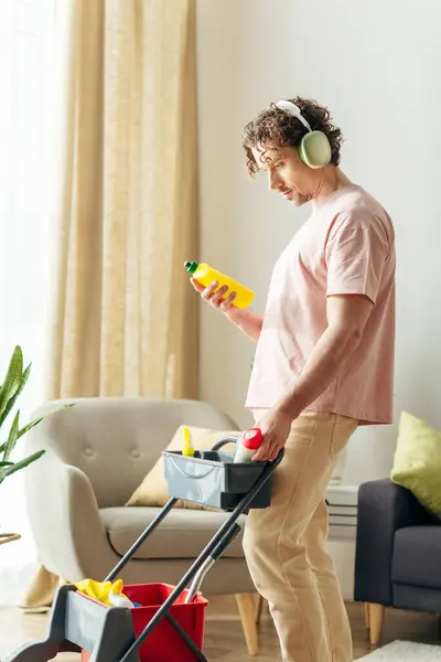 Ein Stilvoller Mann Homewear Putzt Ein Gemütliches Wohnzimmer Mit Kopfhörern Stockbild