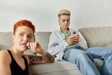 Two people, a lesbian couple with short hair, sit on a couch absorbed in phone, disconnected from each other. clipart