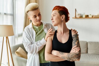 Two women with short hair engaging in a conversation in a cozy living room setting. clipart