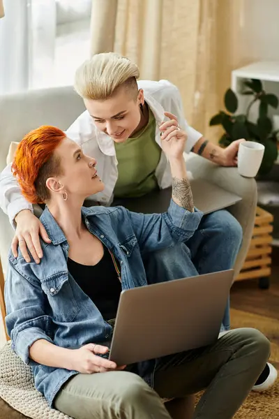 stock image Two women with short hair sit on a couch, engrossed in a laptop screen, cozy and focused.