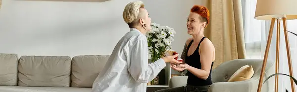 Two women with short hair, a lesbian couple, sitting on a cozy couch in a stylish living room, enjoying a relaxing moment together.