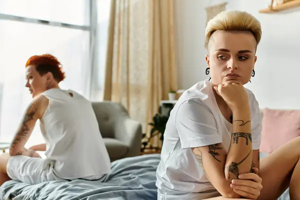 タトゥーを持つ2人の女性 レズビアンのカップルは ベッドルームのベッドに座って 関係の困難を示しています — ストック写真