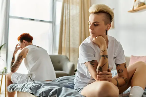 女性は タトゥーとともに ベッドルームのベッドに密接に座り スタイルとつながりの独特な感覚を示しています — ストック写真