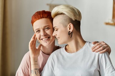 Kafası tıraşlı lezbiyen bir çift yatak odasında kendine güvenen bir poz veriyor. Eşsiz tarzlarını kucaklıyor ve LGBT yaşam tarzlarını kutluyorlar..