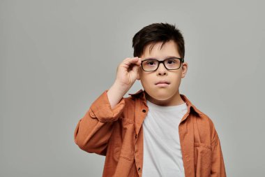 Down sendromlu çekici bir çocuk gri arka planda poz veriyor..