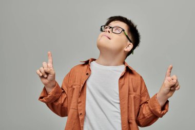 Down sendromlu gözlüklü küçük çocuk yukarı bakıyor..
