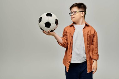 little boy with Down syndrome with glasses holding a soccer ball. clipart