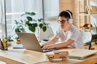 Child with Down syndrome with headphones, laptop, home setting. clipart