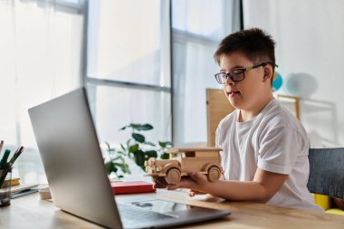 Down sendromlu sevimli çocuk dizüstü bilgisayarında tahta oyuncakla yaratıcı bir şekilde oynuyor..