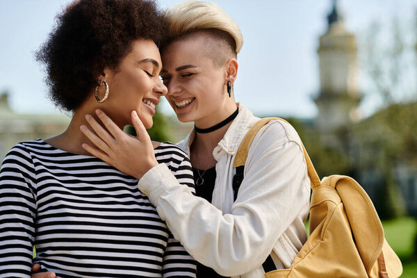 Two young women embrace each other warmly in a park, their faces expressing love and joy in this tender moment.