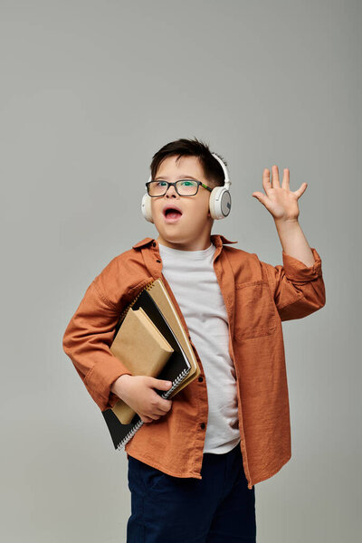 little boy with Down syndrome, wearing headphones and holding books.