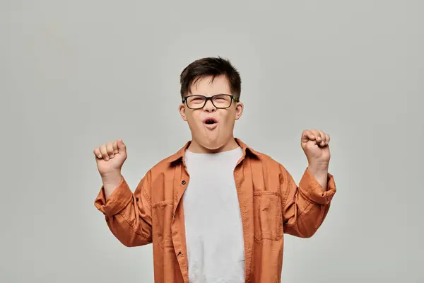 stock image A little boy with Down syndrome lifts his hands in the air with excitement.