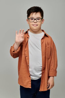 A charming little boy with Down syndrome, wearing glasses, strikes a pose for the camera. clipart