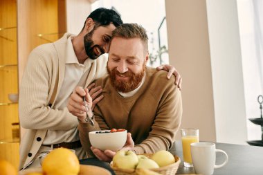 İki mutlu adam, gay bir çift, modern bir mutfakta birlikte yemek yiyorlar, sevgi ve bağlantı gösteriyorlar..