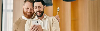 İki sakallı adam, modern bir apartmanın aynasında birbirlerine bakıyorlar. Birbirlerine sevgilerini ve bağlarını gösteriyorlar..