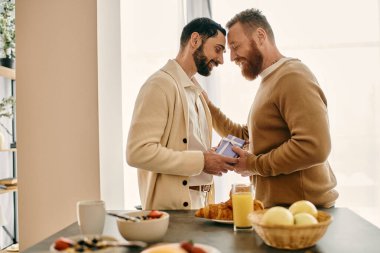 İki sakallı adam bir mutfakta duruyor, modern dairelerinde bir anlık mutluluk ve bağlarını paylaşıyorlar..