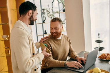 Two men, a happy gay couple, are focused gift near laptop clipart