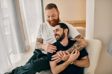 Modern bir oturma odasında birbirine sarılıp sevgilerini ve sevgilerini ifade eden iki adam..