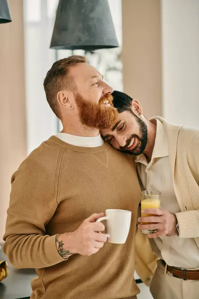 stock image A happy gay couple embraces while enjoying a cup of coffee in their modern kitchen.