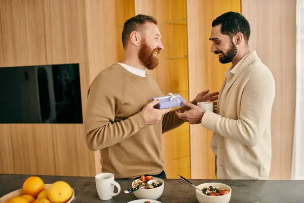 stock image A happy gay couple are laughing and exchanging gifts in a bright, modern kitchen, showcasing their love and affection.