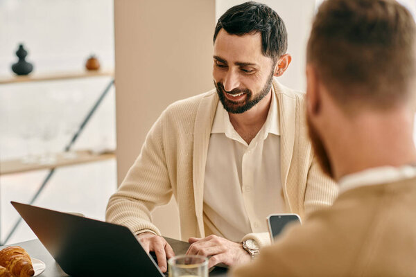 Two men immersed in discussion near laptop in a cozy setting.