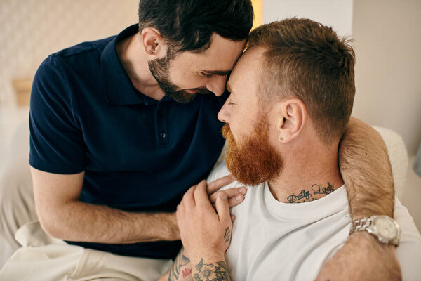 Two men, a happy gay couple, embracing each other on a couch in a modern living room.
