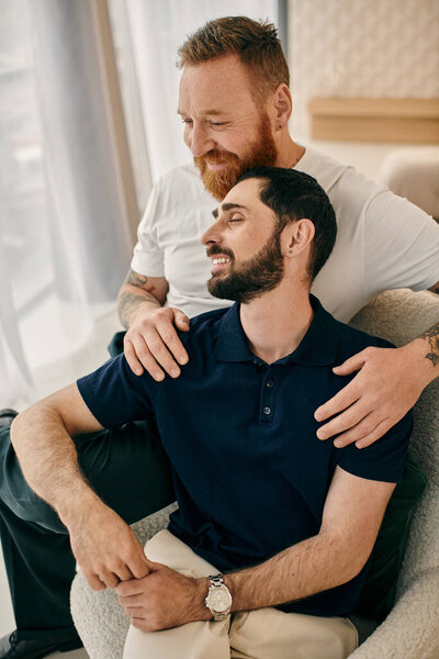 Two men in casual clothes hugging warmly on a cozy couch in a modern living room, expressing their affection and deep connection.