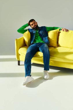 Sarı bir kanepenin üzerinde mutlu bir şekilde oturan Afrikalı bir Amerikalı.