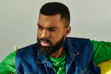 Sakallı bir adam mutlu bir şekilde parlak sarı bir koltukta oturur, rahatlama duygusu somutlaştırır..