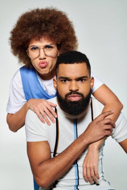 Gri arka planda Afro-Amerikalı bir kadın tutan Afro-Amerikalı adam, arkadaşlığı simgeliyor..