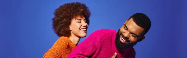 stock image A young African American man and woman hug each other warmly, showcasing friendship and connection in vibrant casual attire.