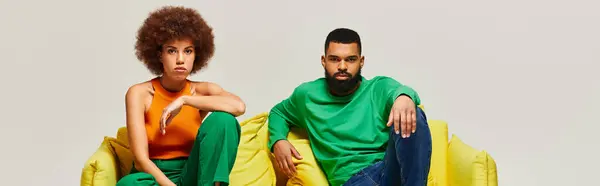 Afroameričtí Přátelé Pulzujících Šatech Sedí Žlutém Gauči Ukazují Silné Pouto — Stock fotografie