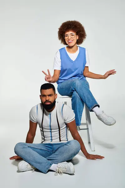 stock image An African American man and woman in stylish attire sit closely, showcasing friendship and camaraderie.